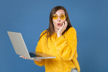 Surprised excited shocked amazed young brunette woman 20s in yellow fur sweater eyeglasses posing...