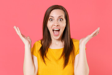 Shocked amazed excited surprised young brunette woman wearing yellow casual t-shirt posing keeping...