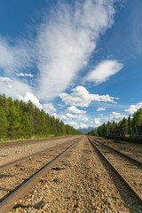 Fototapeta premium Railroad Tracks leading into distant snow capped mountains in Canada