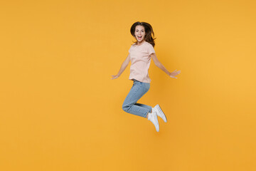 Fototapeta na wymiar Full length side view portrait of excited cheerful funny young woman 20s wearing pastel pink casual t-shirt posing jumping spreading hands looking camera isolated on yellow color background studio.