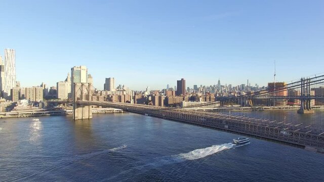 Vista a&eacute;rea panor&aacute;mica a detalle del Puente de Brooklyn y el R&iacute;o Este en Manhattan con un par de lanchas navegando durante el amanecer.