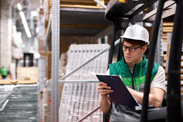 caucasian warehouse worker is checking his list on clipboard in warehouse, transportation logistics...