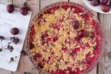 Plum pie with crumble on wooden table