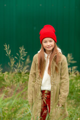 A girl in ordinary autumn clothes on a background of bushes