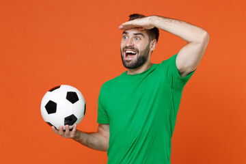 Excited man football fan in green t-shirt cheer up support favorite team with soccer ball hold hand...