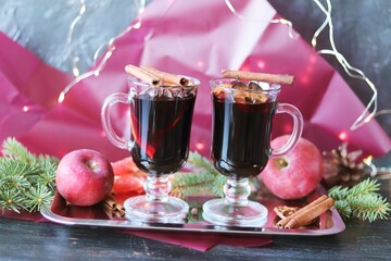 Merry Christmas, cups with mulled wine, spices, fruits, fir branches on a dark wooden table, home comfort concept, seasonal winter holidays