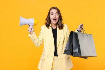 Surprised young woman 20s wearing basic light suit jacket hold package bags with purchases after...