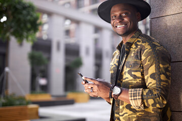 fashionable african man hold mobile phone in hands outdoors, chatting with someone or surfing the Net