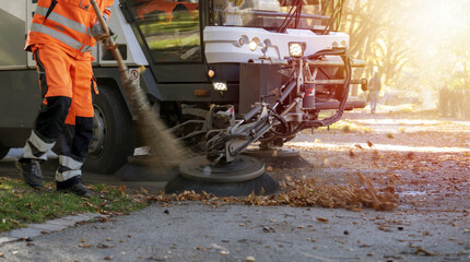 New generation of small electric street sweeper removing fallen leaves in body at autumn city park....