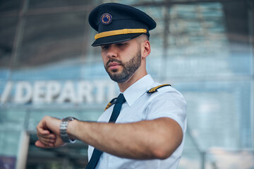 Handsome male pilot looking at wristwatch on the street © Svitlana