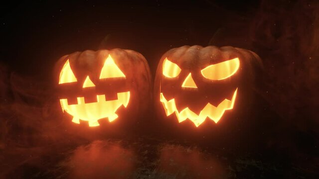 Halloween pumpkins are burning, glowing and sparkling from the inside on a black background with smoke. Ultra HD 4k seamless loop animation for festive horror decoration.