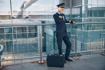 Handsome male pilot talking on cellphone at airport