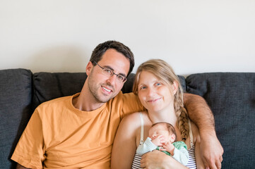 Happy parents with newborn on sofa