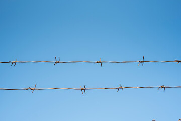 Barbed wire fence over blue sky
