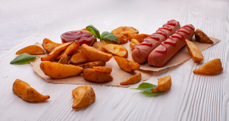 Delicious sausages with fried potatoes and ketchup on a wooden table