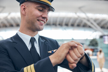 Cheerful male pilot looking at wristwatch and smiling © Svitlana