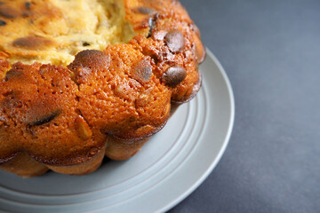 part of a round pie with pumpkin seeds from corn and rice flour on a gray plate on a black background side view . gluten free baked goods made at home