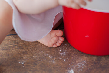 Little chef in apron and a suit of a cook, sits on a dark wooden background. Chef's hat on her head. She is a bakery. Close up. 