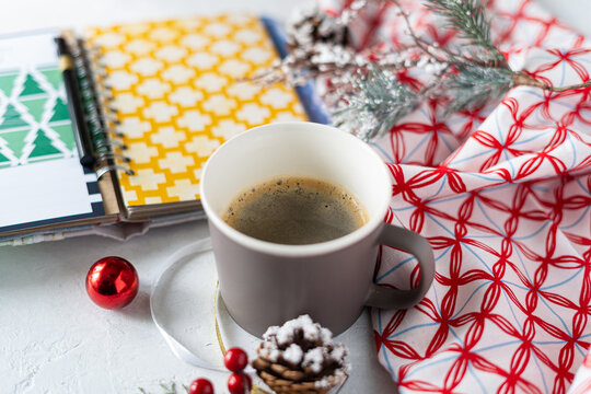 Cup of coffee, holiday decorations, cone and notebook, christmas planning concept. Happy new year