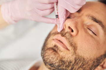 Unshaven young man receiving cosmetic injection at wellness center
