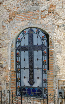 Puerto Vallarta, Mexico - April 25, 2008: Church of Our Lady of Guadalupe. Stained glass window with dark gray cross and red flower images in outside wall.