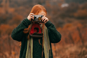Girl with red hair takes a picture with a vintage camera