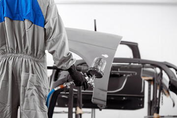 close-up photo of male hands holding machine for painting car, he is ready to work. cropped man in protective uniform