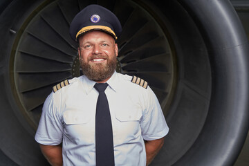 Contented pilot posing in front of the plane part