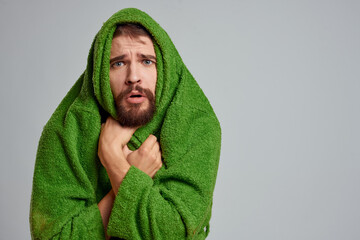 Bearded man in green robe cropped view gray background close-up