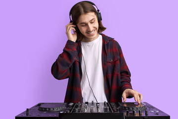 positive male DJ playing music on purple background, caucasian long haired man in casual wear...