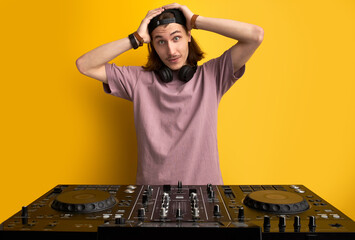 surprised man hold head in shock standing in front of dj equipment, doesn't know how to play on it