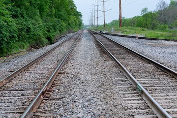 Naklejka premium View of a double steel railroad tracks with trees on the side of the road. 