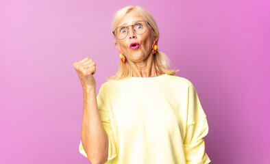 middle age woman looking astonished in disbelief, pointing at object on the side and saying wow,...