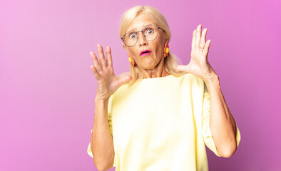 middle age woman looking shocked and astonished, with jaw dropped in surprise when realizing...