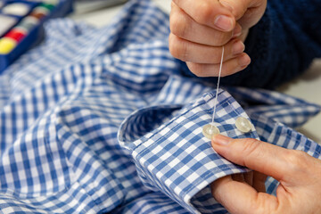 Costurera cosiendo un botón a la camisa