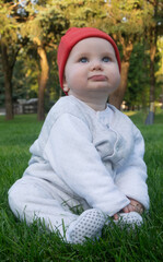 Dreamy baby girl sitting on a beautiful manicured lawn made of grass in the Park