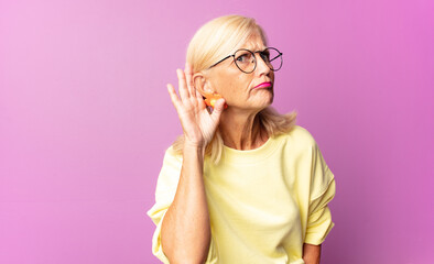 middle age woman looking serious and curious, listening, trying to hear a secret conversation or...
