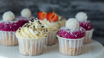 made dish of delicious cupcakes with white cream decorated with ripe strawberries on a gray blue background.