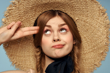 Girl in a straw hat portrait close-up pigtails fun red hair blue background