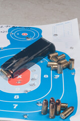 top view, medium distance of a 9 mm magazine with 9 mm defensive  and 9 mm shell casings on a used, paper target