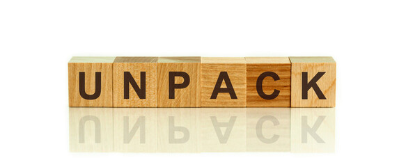 Modern business buzzword - UNPACK. Word on wooden blocks on a white background. Close up.
