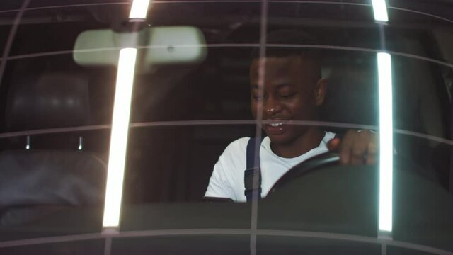 African American young man driving a car, smiling at the camera