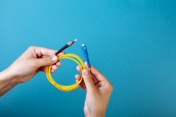woman's hands hold SC and FC connector fiber optic patch cord single mode on blue background