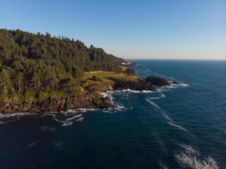 The nature view on the ocean, rocks and forest. The sunny weather, blue clean sky, calm water. Green rocks in the ocean. Wallpaper. Blue water background.