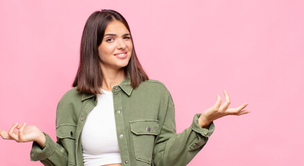 young pretty woman shrugging with a dumb, crazy, confused, puzzled expression, feeling annoyed and...