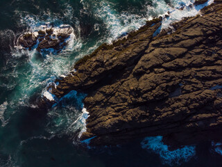 The rocky coast in the raging ocean. Blue water background. The fantastic view with natural landscape. Sunny weather. Idea for wallpaper.