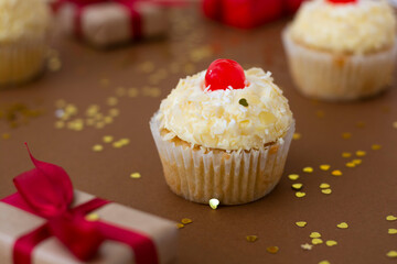 Cupcake with vanilla butter cream, brown background with gift boxes, birthday concept. Sweet dessert.