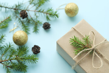 Fototapeta na wymiar Christmas composition. Gift box decorated with a sprig of spruce in an ecological style on a blue background. Selective focus. 
