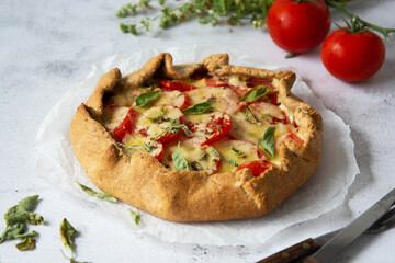 Homemade tomato tart or galette. Whole wheat rustic pie with tomatoes, cheeseand herbs. Healthy food concept.