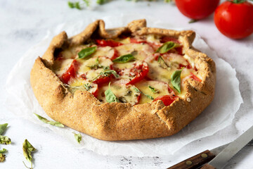 Homemade tomato tart or galette. Whole wheat rustic pie with tomatoes, cheeseand herbs. Healthy food concept.